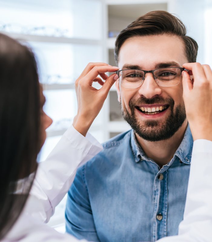 Young,Female,Doctor,Ophthalmologist,Is,Helping,Handsome,Man,To,Choose